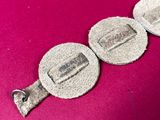 two pieces of silver metal on a pink surface
