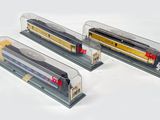 trois trains miniatures exposés dans une vitrine