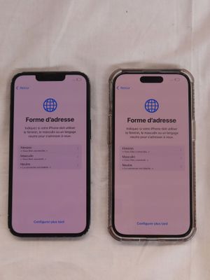 deux iPhones posés côte à côte sur un lit recouvert d'un drap blanc