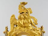 a gold clock with an angel sitting on top of it