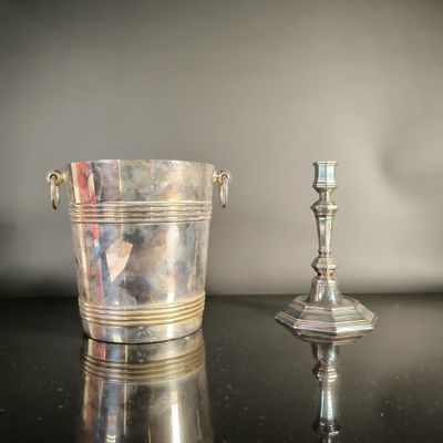 a silver bucket and a silver candle holder on a table