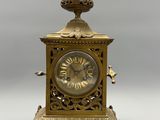 a gold clock with a bird on top of it