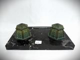 two small green houses sitting on a black base