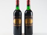 two bottles of red wine sitting next to each other on a white surface
