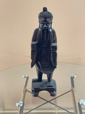une statue représentant un homme assis sur une table en verre