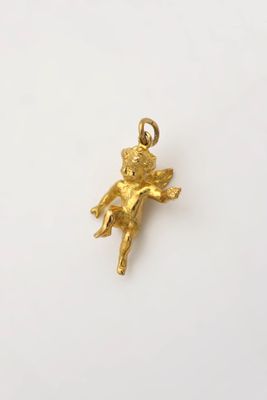 un pendentif en or sur lequel est représenté un petit ange, sur le dos