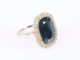 a close up of a ring with a blue stone surrounded by diamonds