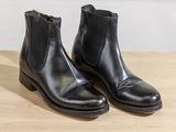 a pair of black boots sitting on top of a wooden table