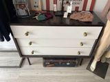 a chest of drawers that has a suitcase on top of it