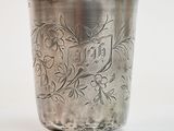 a silver cup with a design on it on a white surface