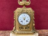 une horloge en or posée sur une table en marbre, avec un mur rouge en arrière-plan