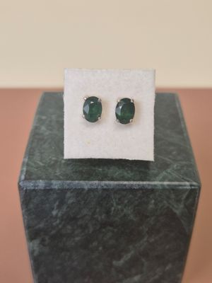 a close up of a pair of emerald earrings on a marble block