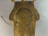 a gold clock hanging from the ceiling with a bird on top