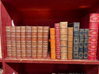 de nombreux livres anciens sur une étagère dans un meuble rouge