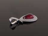 a close up of a red stone and diamond pendant on a black surface