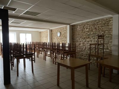 Des tables et des chaises sont alignées dans une pièce aux murs en pierre