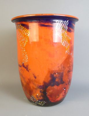 un vase orange posé sur une table, sur fond gris