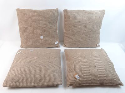 quatre coussins ornés de boutons, posés sur une surface blanche