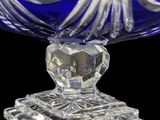 a blue glass bowl with a silver base on a black background