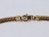 a close up of a gold bracelet on a white surface