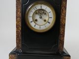 une horloge noire avec un cadran doré sur fond blanc