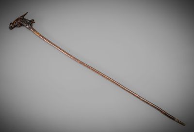 an old wooden stick with a metal handle on a gray background