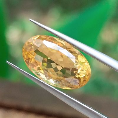 un gros plan d'un diamant jaune tenu par une paire de pinces