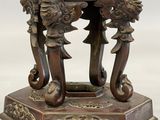 a bronze vase on a stand on a white surface