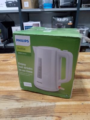 packaging of a white electric kettle sitting on top of a wooden table
