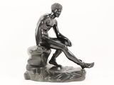 statue of a man sitting on a rock on a white background