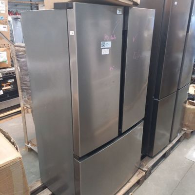 several stainless steel refrigerators are stacked on pallets in a warehouse