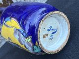 a blue vase with a bird on it sitting on a table