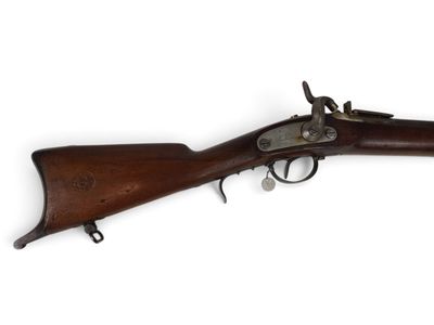 un vieux fusil exposé sur une surface blanche