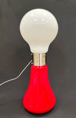 une image représentant une lampe rouge et blanche posée sur une surface noire