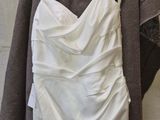 wedding dress hanging on a hanger in front of a white wall
