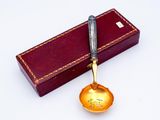 a gold spoon with a handle on a red box