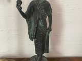 a bronze statue of a woman holding a bird on a table