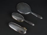 three silver plated brushes and a brush on a black surface
