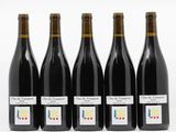 quatre bouteilles de vin sont alignées sur une surface blanche