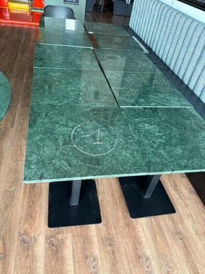 une table avec un plateau en marbre vert et des pieds en métal noir
