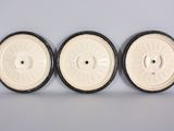 three white and black wheels are lined up on a white surface