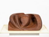 a wooden sculpture on a white pedestal with a white background