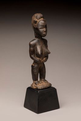 une statue en bronze représentant une femme tenant un bébé dans ses bras, posée sur un socle noir