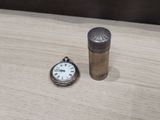 a small silver pocket watch next to a small silver pocket watch