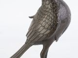 un oiseau en bronze posé sur une surface blanche