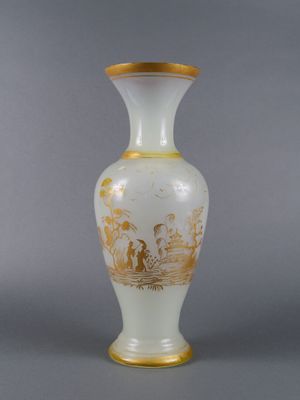 a white vase with gold decoration on it on a gray surface
