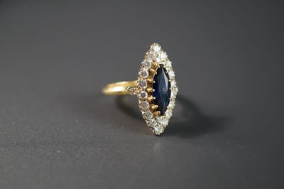 gros plan d'une bague en or avec un saphir et des diamants