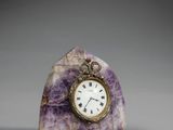 horloge en marbre violet posée sur un socle, avec un cadran plaqué or