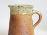 a brown and green mug sitting on a white surface