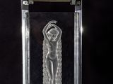 a glass sculpture of a nude woman on a black background